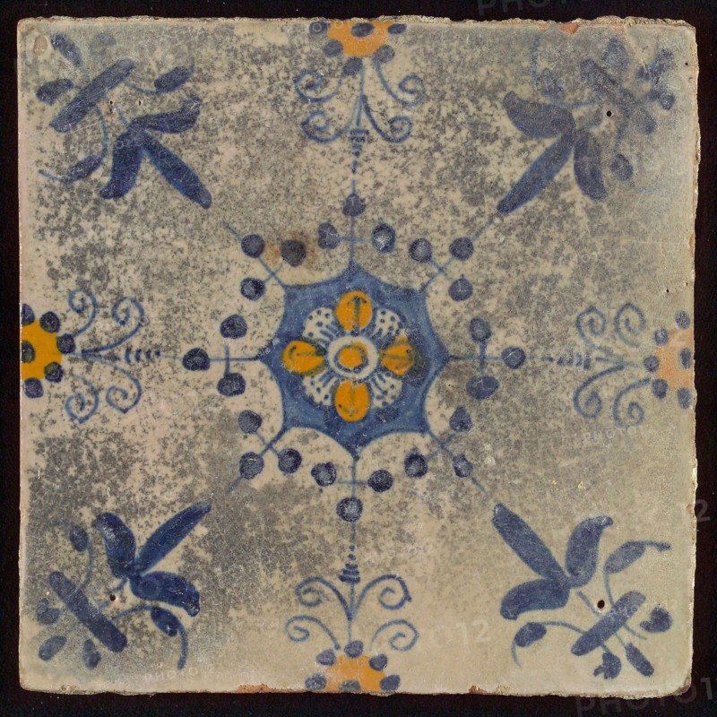 Tile, blue draft and orange on white, central flower within star shape, three-spot around, half rosette, corner pattern lily