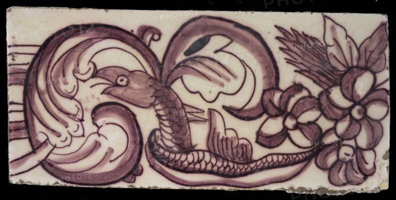 Rectangular edge tile in purple with swirling design of leaves, flowers and twisted snake with scales and fin, border tile wall