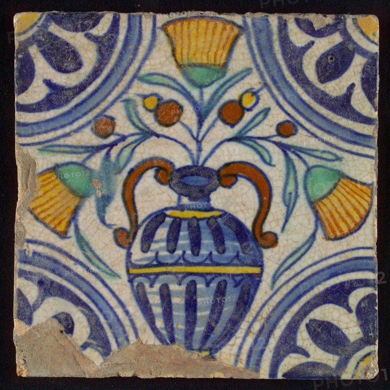 Tile, blue draft, orange, yellow, brown and green on white, central flowerpot with marigolds, corner pattern, rosette, wall tile