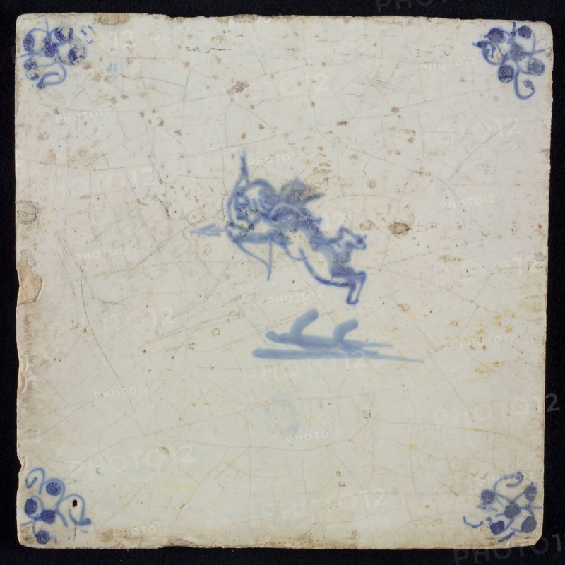White tile with blue flying cupid with bow and arrow; corner motif spider, wall tile tile sculpture ceramic earthenware glaze