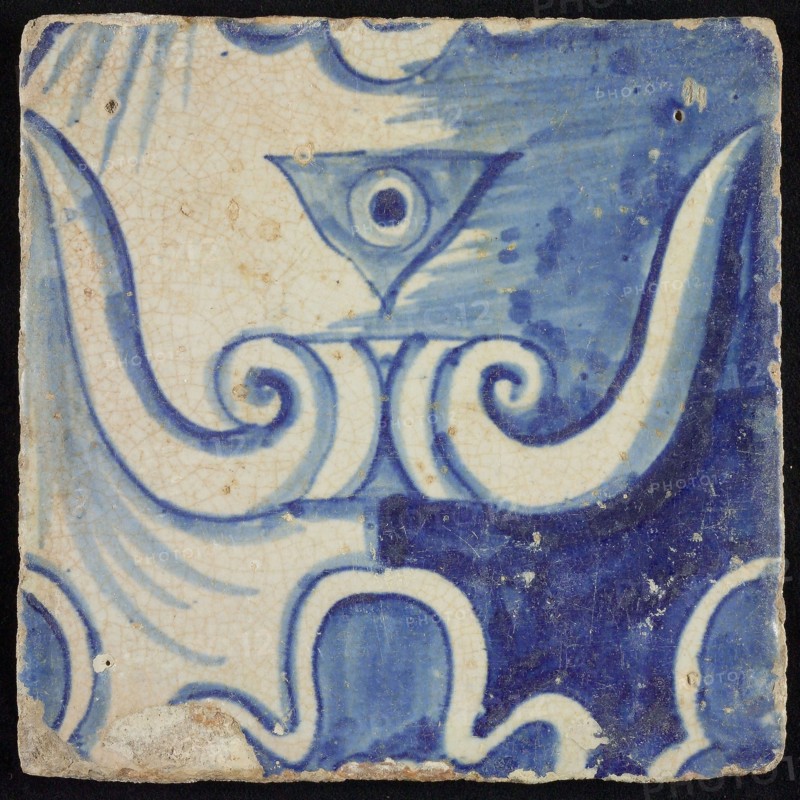 Tile of chimney pilaster, blue on white, part of capitals with stylized triangular navel and groin curls of caryatid, chimney