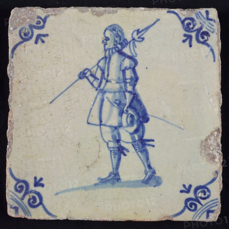 White tile with blue warrior with spear, sword and hat in hands; corner pattern ox head, wall tile tile sculpture ceramics