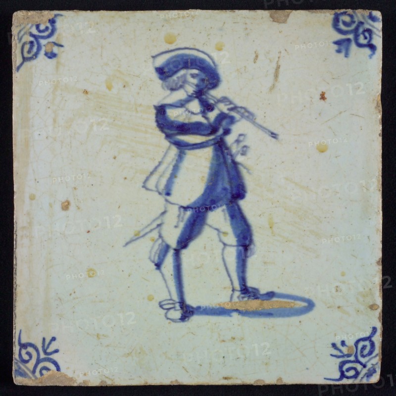 White tile with blue flute-playing warrior with hat; corner pattern ox head, wall tile tile sculpture ceramics pottery glaze