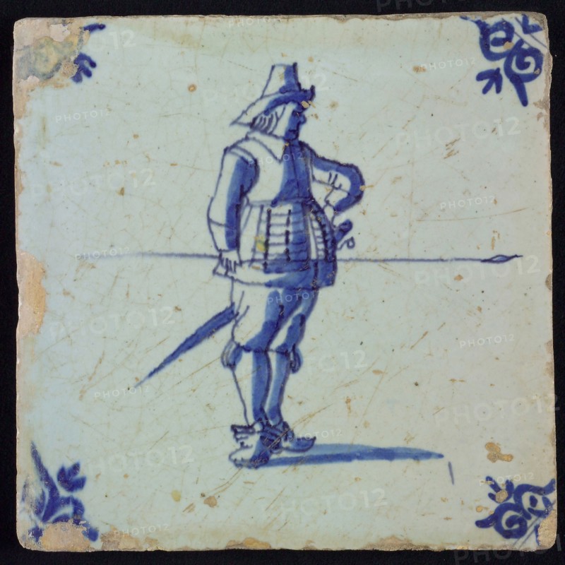 White tile with blue warrior with spear and hand in side; corner pattern ox head, wall tile tile sculpture ceramic earthenware