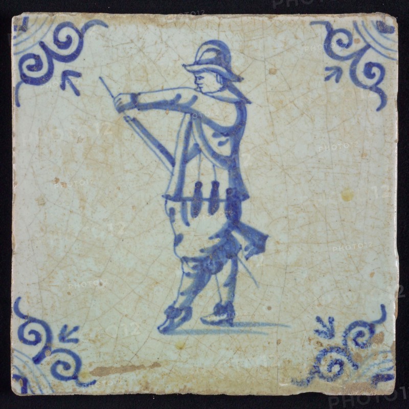White tile with blue warrior with helmet, loading his rifle; corner pattern ox head, wall tile tile sculpture ceramic
