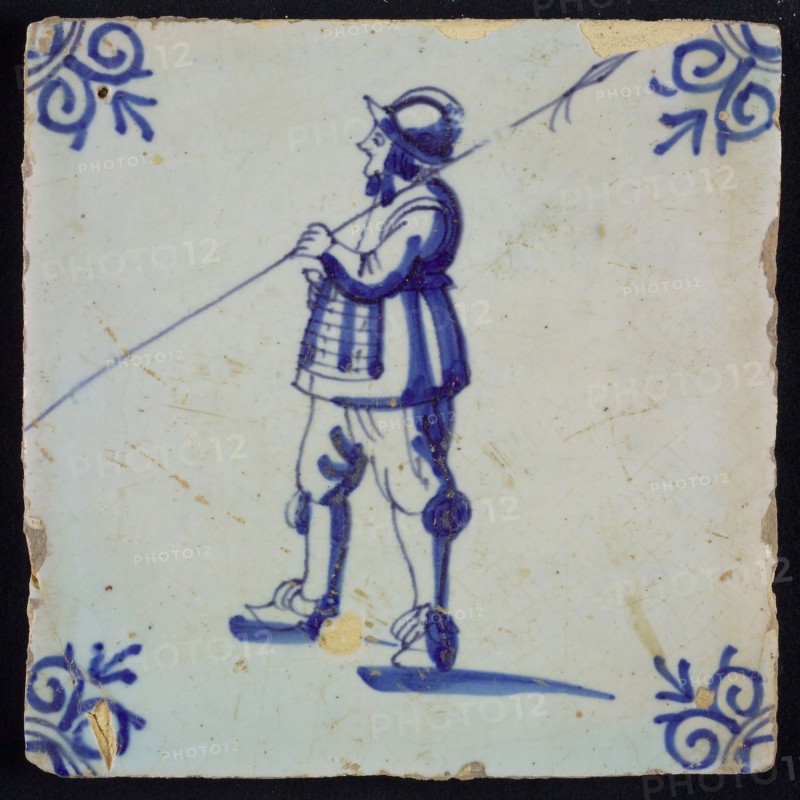 White tile with blue warrior with spear and helmet; corner pattern ox head, wall tile tile sculpture ceramic earthenware glaze