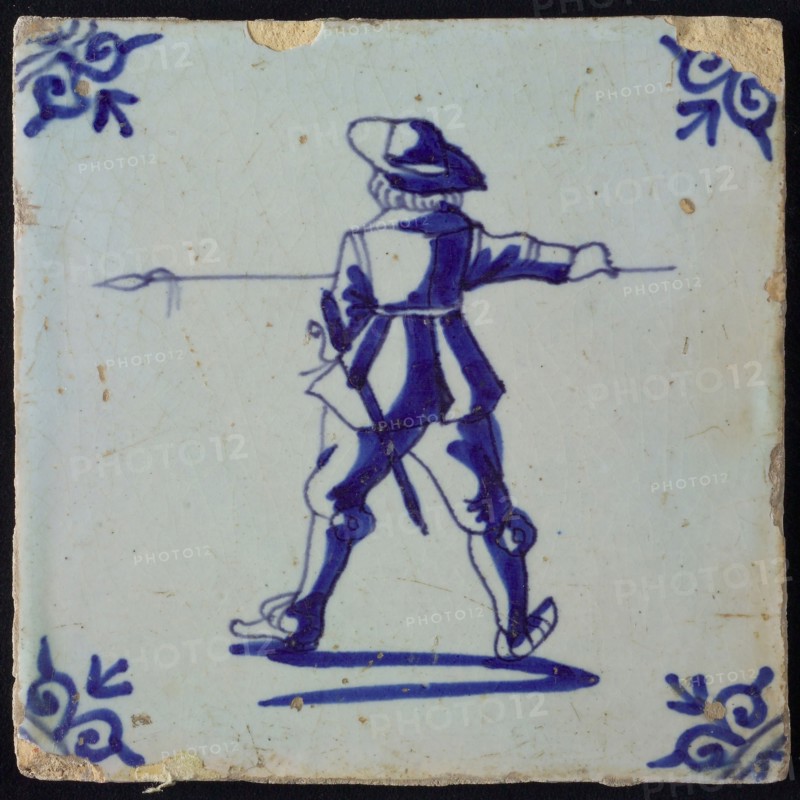 White tile with blue warrior with spear, seen from behind; corner pattern ox head, wall tile tile sculpture ceramics pottery