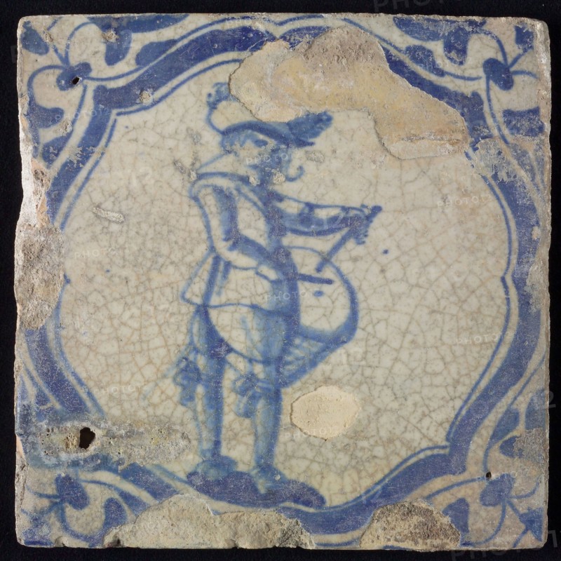 White tile with blue warrior with drum in accolade-shaped frame, corner motif wing leaf, wall tile tile sculpture ceramics