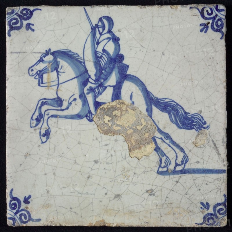 White tile with blue horseman with armor, shield and sword; corner pattern ox head, wall tile tile sculpture ceramic earthenware
