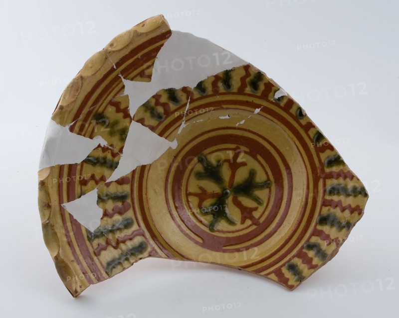 Earthenware dish on stand with wavy saucer edge, clear sludge decoration in yellow and green, dish plate crockery holder soil