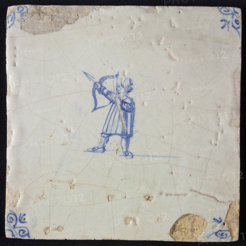 White tile with blue warrior shooting with bow and arrow; corner pattern ox head, wall tile tile sculpture ceramics pottery