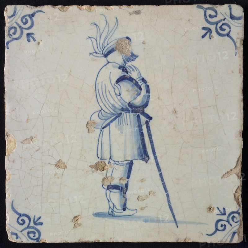 White tile with blue warrior leaning on stick; corner pattern ox head, wall tile tile sculpture ceramic earthenware glaze, baked