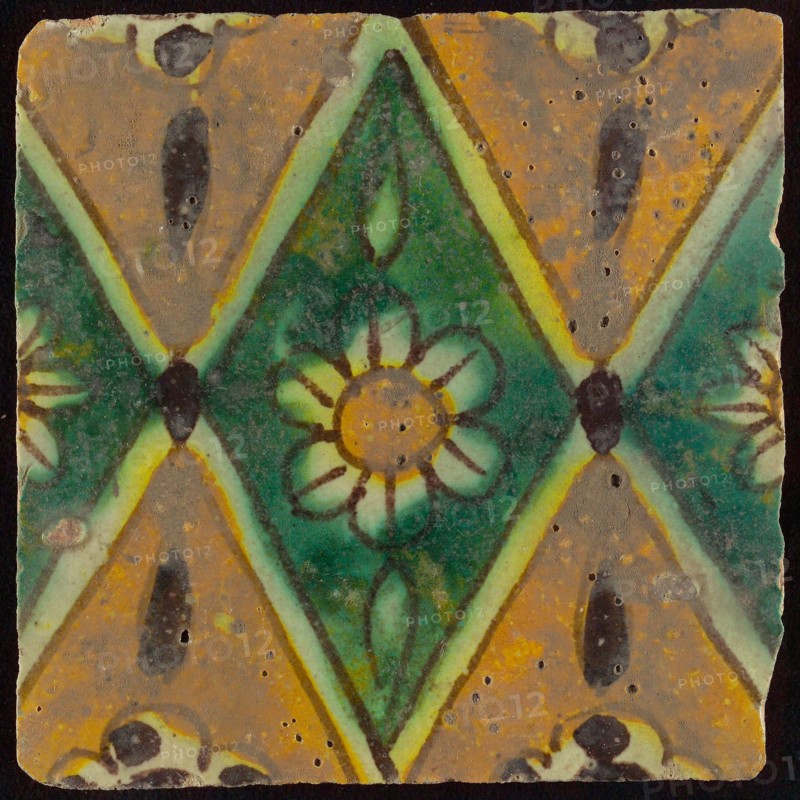 Floor tile, brown draft, green and yellow on white ground, central green oblique glass in which white flower with yellow heart