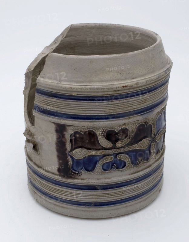 Stoneware mug with stylized floral band around belly, blue piping, purple and blue glaze, pulp drinking utensils tableware