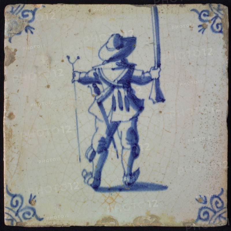 White tile with blue warrior on the back seen with rifle and stand; corner pattern ox head, wall tile tile sculpture ceramic