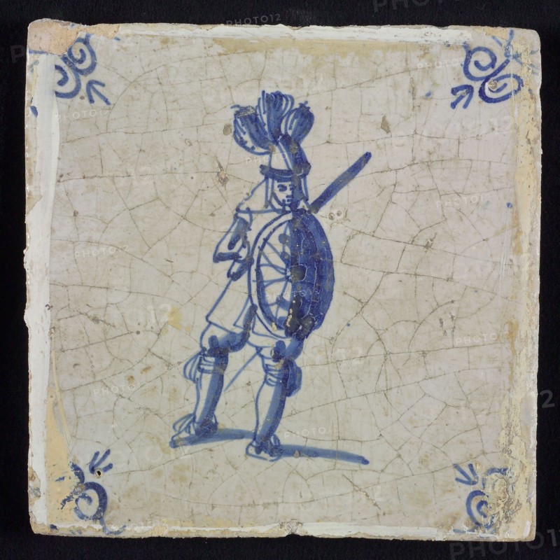 White tile with blue warrior with sword and shield; corner pattern ox head, wall tile tile sculpture ceramic earthenware glaze