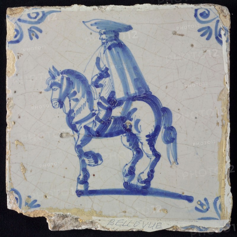 White tile with blue rider with cape and hat; corner pattern ox head, wall tile tile sculpture ceramic earthenware glaze, baked