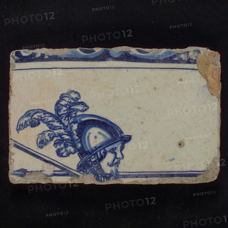 Piece of tableau tile with edge decorated in blue and man with helmet and skewers, tile picture footage fragment ceramics