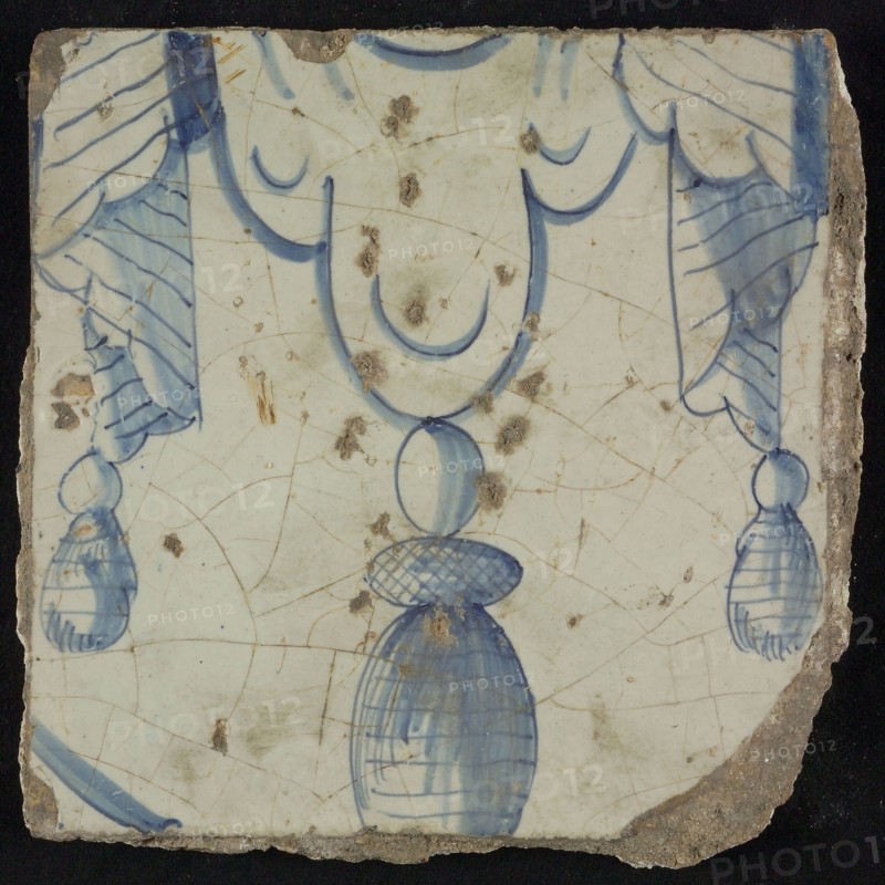 Tile of chimney pilaster, blue on white, bottom of pleated lap with three hanging tassels, chimney pilaster tile pilaster