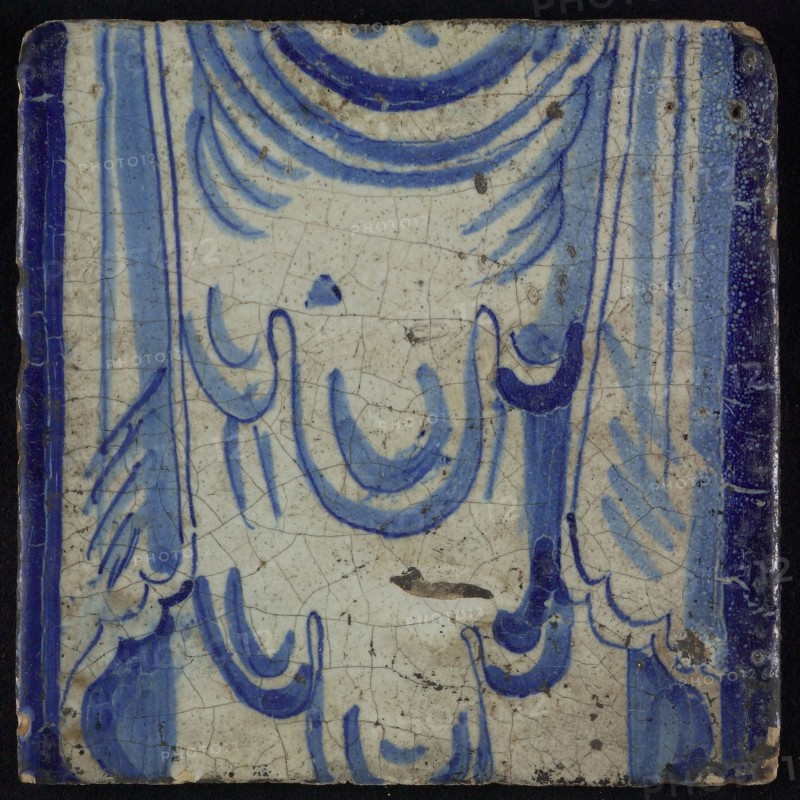 Tile of chimney pilaster, blue on white, upper part of shell-like headdress and two curly floral ornaments, chimney pilaster