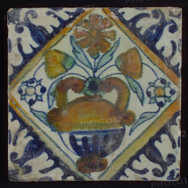 Tile in orange, brown, green, and blue on white, flowerpot in square, corner pattern palmet, wall tile tile sculpture ceramic