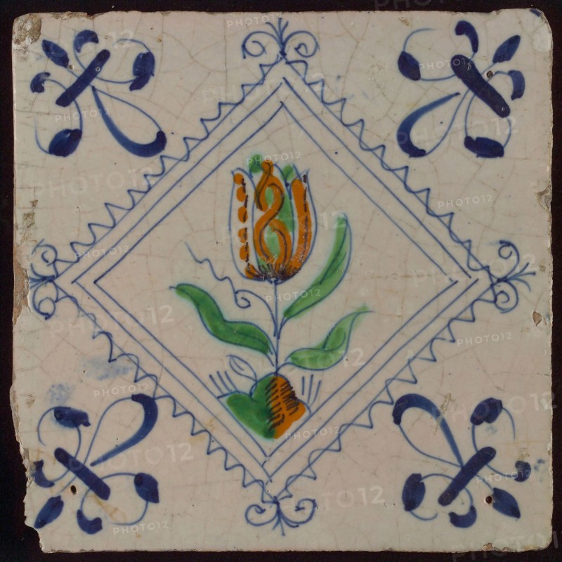 Tile, tulip on ground in orange, green and blue on white, inside serrated square with plume, corner pattern french lily, wall