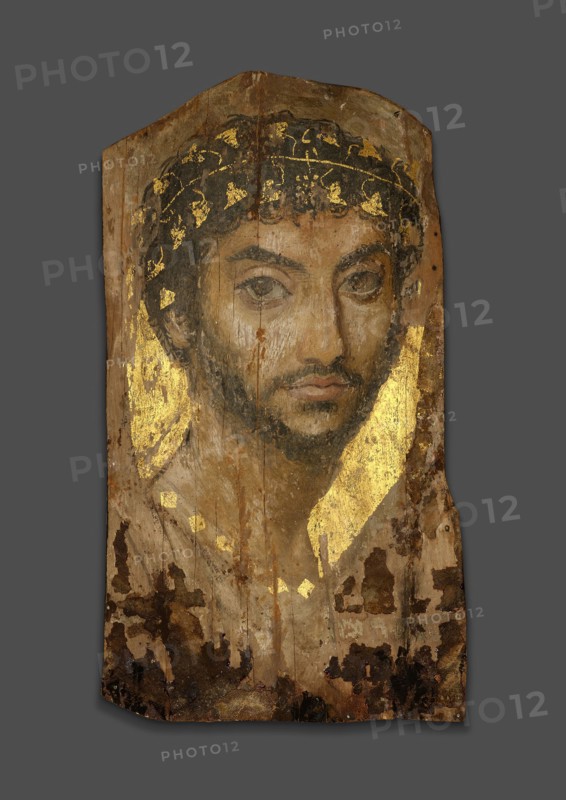 Mummy Portrait of a Man Wearing an Ivy Wreath, Early to mid–2nd century AD, Roman, The Fayum, Egypt, Fayum, Lime (linden) wood, beeswax, pigments, gold, textile, and natural resin, 39.4 × 22 × 0.2 cm (15 1/2 × 8 5/8 × 1/16 in.), depth with support 3.5 cm (1 3/8 in.)