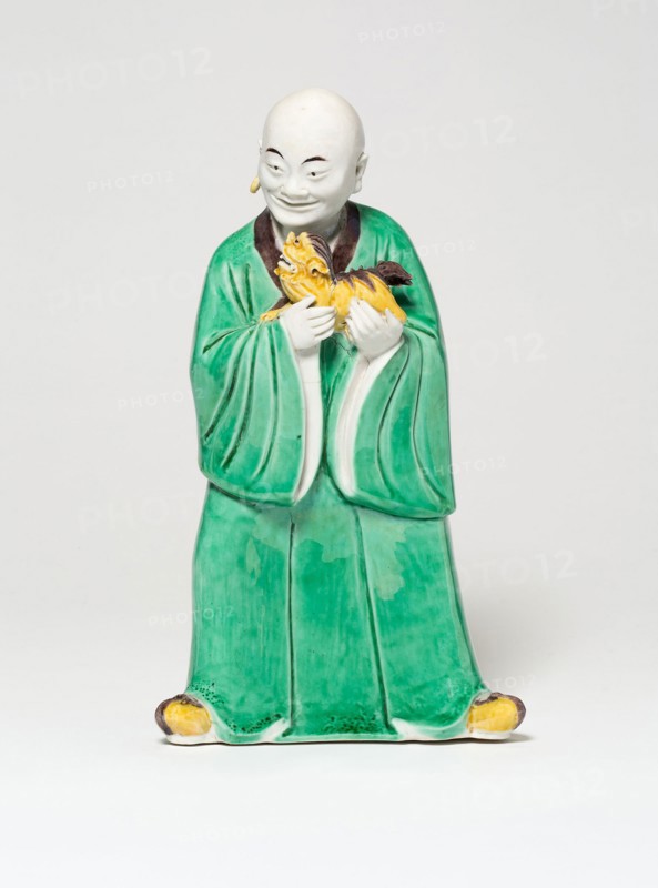 Seated Luohan Holding a Lion, Qing dynasty (1644–1911), c. 19th century, China, Porcelain painted in green, yellow, and aubergine glazes, 19.1 × 10.8 × 6.9 cm (7 1/2 × 4 1/4 × 2 3/4 in.)