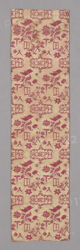 Panel, c. 1720, England or France, England, silk, satin weave with supplementary patterning wefts and self-patterned by areas of weft-float faced twill weave, two selvages present. Central cartouche with inscription surrounded by regularly placed carpenter's tools, say, compass, drill, plane, and mallet, in red on off-white ground, 223.3 × 57.1 cm (87 7/8 × 22 1/2 in.)