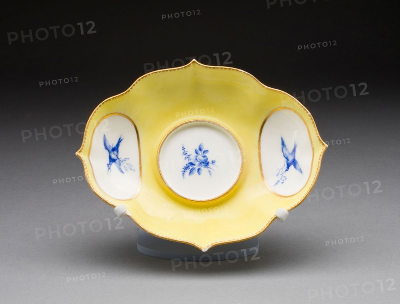 Stand for a Mustard Pot, 1751/52, Vincennes Porcelain Manufactory, French, founded 1740 (known as Sèvres from 1756), Painted by André-Vincent Vielliard (French, 1717-90, active 1752-90), Vincennes, Soft-paste porcelain, yellow ground, monochrome blue enamel, and gilding, 3.6 x 13.7 x 17.4 cm (1 3/8 x 5 3/8 x 6 13/16 in.)