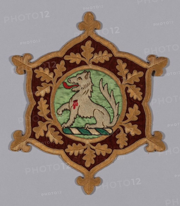 Myddelton Biddulph Armorial Medallion, c. 1846, Designed by Augustus Welby Northmore Pugin (English, 1812–1852) for Chirk Castle Red Drawing Room and Saloon, England, Wales, Wrexham, Chirk, Wales, Linen, plain weave, appliquéd with medallion of silk, satin weave, appliquéd with padded linen, plain weave, embroidered with wool, silk, cotton and silk- wrapped cotton and silk and cotton tubular braided cord in satin, single satin, split, and stem stitches, laidwork and couching, glass eye and appliquéd with silk, plain weave with supplementary pile warps forming cut solid velvet, embroidered with silk and silk-wrapped cotton in paper padded satin stitches, couching, 42.2 x 36 cm (16 5/8 x 14 1/8 in.)