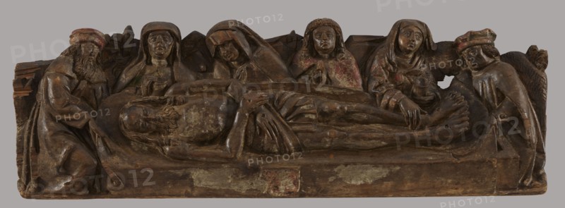 The Entombment - bas-relief probably fragment of a predella, unknown artist Mazovia, The Entombment iconographic, repossession Krakow, provenance unknown. The bas-relief is a rectangle; in the foreground a figure of Christ lying horizontally on a sheet supported by two men, hips covered with a perizonium, arms crossed on the perizonium, nail marks on the hands and legs. Legs stiffly outstretched, parallel. In the background, four busts: in the centre, Mary with her head bowed towards Christ, on her left a frontally positioned female bust, her gaze directed straight ahead. On the right, a frontally depicted Saint. John the Evangelist with hands folded in prayer. To the right of St. John, a female figure touching Christ's feet. The sides of the composition are closed by two men shown en trois quarts. An illegible coat of arms is on the front. DMR, after 1500 According to Walicki, Polska sztuka gotycka, p. 34, it comes from an unknown town in the Lowiecko district, from an unknown worksho...