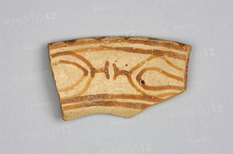 Fragment of a bowl, unknown northern Mesopotamian workshop; painted pottery, geometric ornaments; bucranium ornament; Szarzynska, Krystyna 1918-, author. Upper fragment of the bowl wall with the preserved rim and geometric decoration painted on both sides. On the outer side, a simple geometric ornament consists of two parallel red bands of different widths, separated by an empty stripe in a cream-colored background. On the inner side, in a band bounded by horizontal lines, are two highly schematic, linearly stylized bucraniums bull heads with horns, arranged base to base. The narrow rim is decorated with painted, irregularly rounded triangles, their bases resting on the outer edge. The painted decoration was made before firing, from carefully polished ferrous clay, applied to a dry and very smooth layer of glaze that covered the vessel's surface. After firing, the painting acquired a color ranging from red to dark brown, while the glossy background is cream-colored. Ca. 6500–ca. 5500 B...
