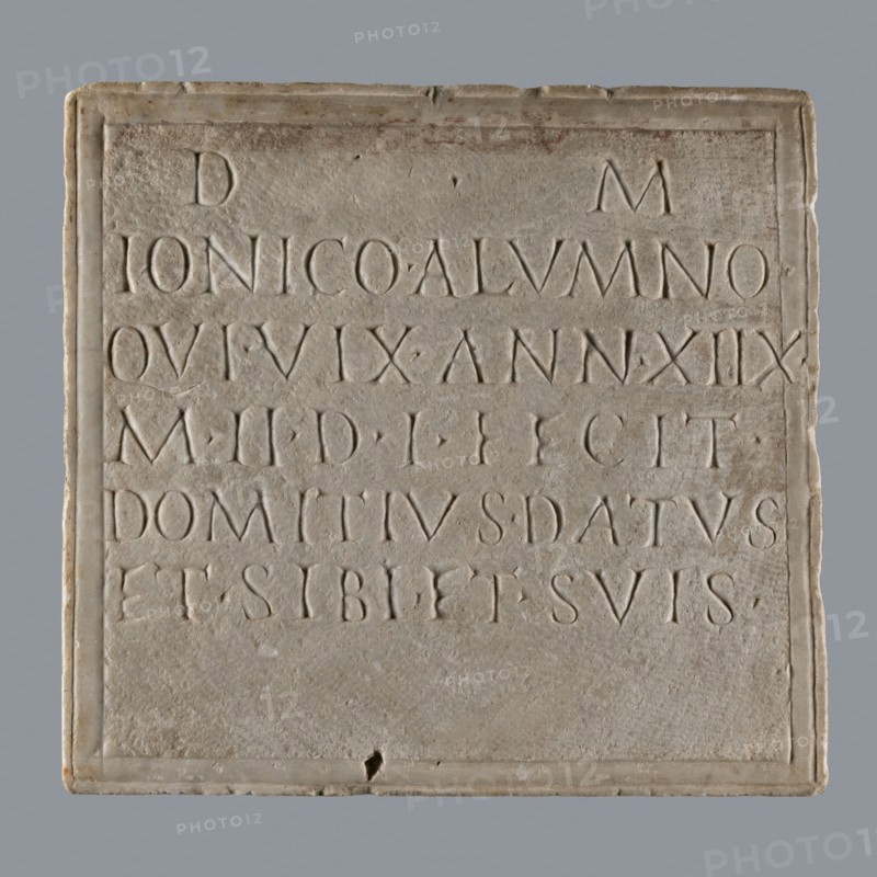 Latin grave inscription, unknown author, 2nd century, Roman Empire 27 BC–476, slab epitaph, grave inscription; height 31 cm, width 28 cm, A square stone plaque with a recessed rectangular panel and a raised border, showing a weathered surface in shades of light gray, beige, and off-white; within the panel a group of carved letterforms are arranged in horizontal lines, their incised shapes creating shallow shadows of slightly darker gray; the plaque edges are slightly rounded and chipped in a few places, and there are faint brownish stains and small pits on the stone surface; the background behind the plaque is a smooth mid-gray.