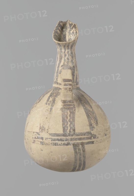 Jug, excavations at Nea Paphos Cyprus — Cypriot pottery, Bronze Age White Painted IV. The jug has a pear-shaped belly, a tall tapering neck, and a three-part spout. The base is gently rounded. A small vertical ribbon-like vise is placed in an arc above the base of the neck. Cream clay with a cream surface. Geometric decoration in black: the neck is covered with densely spaced straight and wavy lines; the interior of the spout is similarly decorated. At the base of the neck this decoration terminates with a horizontal line. The outside of the vise is decorated with three groups of three transverse lines each, and the sides of the vise are painted black. The upper part of the body bears eight sets of two wavy lines radiating from the base of the neck, bordered laterally by straight lines; these extend to about one-third of the body's height where they meet three horizontal lines around the vessel's greatest bulge. In the lower part four sets of three lines branch off from these horizonta...