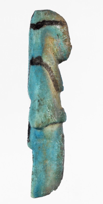 Shabti with baskets on the back. Mummy-shaped funerary figurine, preserved fragment from the knees up. Arms crossed on the chest, hands placed at the same level, holding hoes in each hand. Rectangular basket on the back slung on strings over both shoulders. Long, smooth, three-part wig with a headband; triangular face with proportional details, eyes slightly closed. Painted facial details and headband. Painted inscription in a column separated by vertical lines on the front of the legs, starting just below the folded hands, reading in part ...of the soul belonging to Osiris.... ca. 1069–715 BC; Third Intermediate Period, 21st–23rd Dynasty, Egypt. Shabti; height 7.6 cm, width 3.2 cm., A slender figurine shown in profile with a rounded head, shoulders, and torso, displaying a weathered surface with a mix of turquoise and teal tones, areas of greenish-blue and pale blue, and patches of brown and tan discoloration; there are several dark brown to black horizontal bands and spots across the...