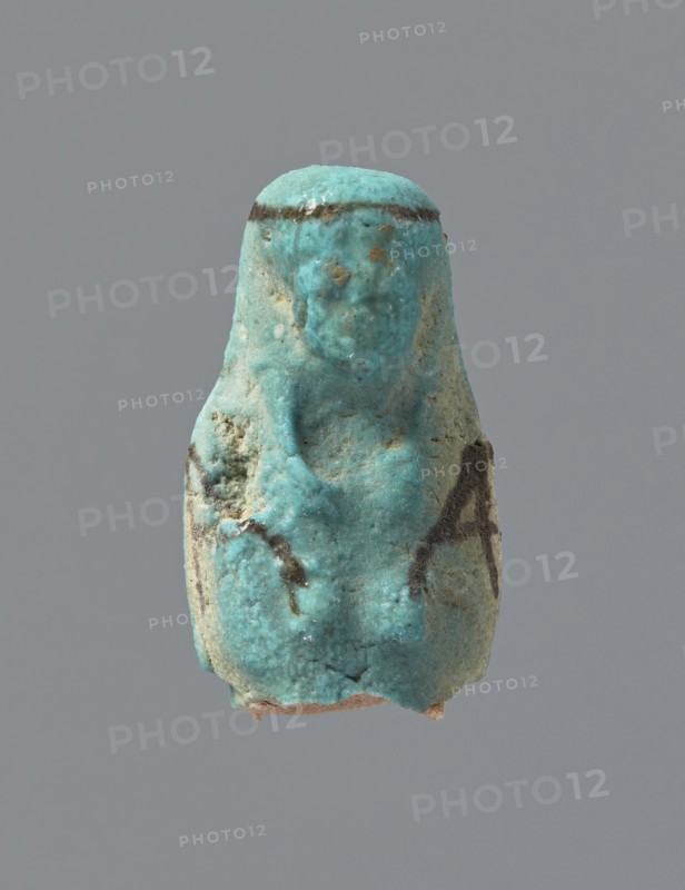 Ushabti, mummy-shaped figurine, funerary gift; preserved head and fragment of torso. Arms crossed on the chest, hands placed at the same level, next to each other, holding hoes in each hand. On the back a square basket is slung on strings over both shoulders. Head with a long, smooth, tripartite wig with a headband. Triangular face, details almost illegible. Headband and tools painted. ca. 945–ca. 715 BC; Third Intermediate Period, 22nd–23rd Dynasty, Egypt. Ushabti; height 3.7 cm, A small turquoise-colored figurine with a rounded top and a textured surface sits against a plain gray background; the object shows a few darker brownish streaks and spots, some lighter pale areas, and a rough, slightly pitted texture with an irregular base and a faint suggestion of a simplified face and body form.