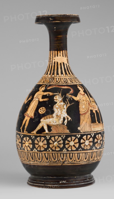 Red-figure bottle vessel depicting the punishment of Marsyas, attributed to Scen.Gal.Klass., Greek pottery, 330–310 BC. Bottle glued from several fragments; minor additions on the neck, flaking of white and yellow retouches covering the silhouette of Silenus. Between ornamental bands on the lower neck and belly, the scene shows Marsyas seated on a cloak one end covering his right thigh, lower torso facing left while upper torso, with hands tied to a tree in front, faces right toward Apollo. Apollo stands beside a table on a platform, a lyre on the table, and in his right hand a taenia victory ribbon that flutters above Silenus’s head. A Scythian stands before Marsyas, holding a knife in his right hand and beginning to flay him. The scene includes three satyrs and a column with an oval object possibly an omphalos. The composition references the musical agon between Apollo lyre and Marsyas aulos. Origin: Apulia, Basilicate findspot. Dimensions: height 26 cm, width 13.5 cm, weight 0.67 kg...