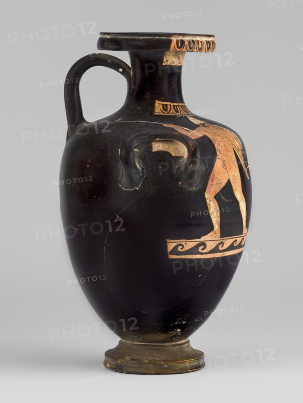 Red-figure hydria with a combat scene, Laghetto-Caivano Group c. 340–320 BC, Duel Painter 340–330 BC. Hydria decorated with a combat scene of two naked hoplite warriors fighting with long spears; they wear pointed helmets, hold round convex shields in their left hands, and wear greaves on their legs. Weaponry painted white with yellow retouching. Ca. 340–320 BC, Campania. Vessel hydria. Height 22.5 cm, width 15.6 cm, depth 13.3 cm, weight 0.612 kg., A black ceramic vessel with a single curved handle and a flared rim, showing a few areas of worn surface and scratches; a figure painted in a reddish-orange hue appears on one side standing on a decorative band, with additional small decorative motifs near the neck and rim in the same reddish-orange color; the vessel sits on a short foot that is a darker brownish color, and the background is a light gray.