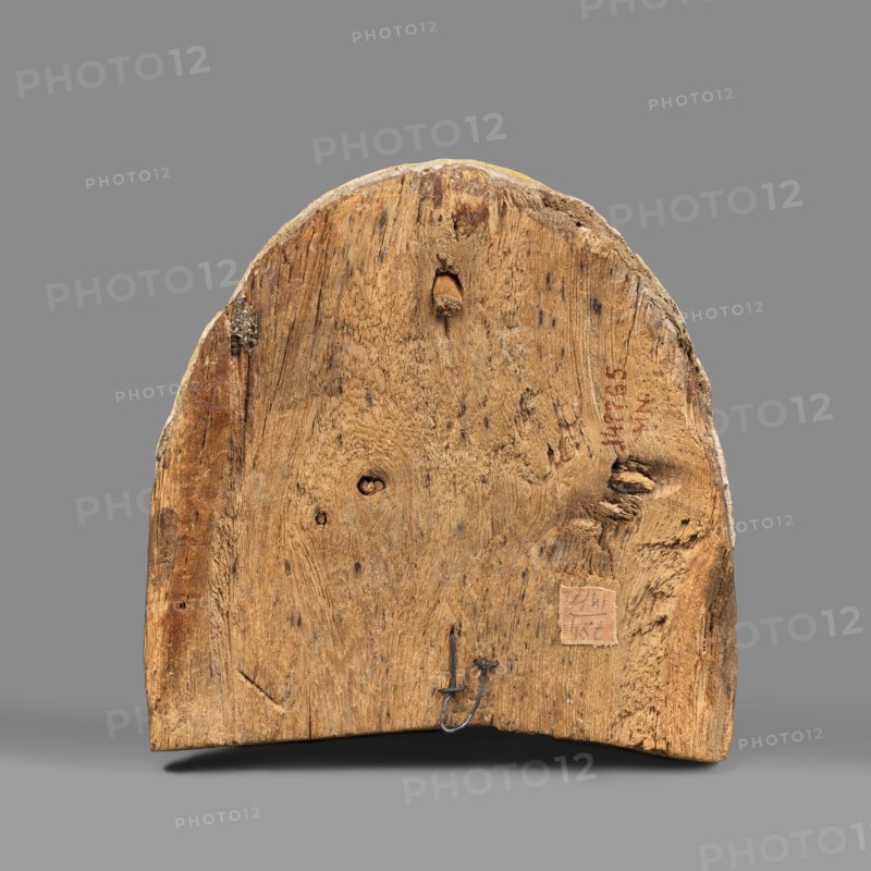 Woman's sarcophagus mask. Mask of wood covered with a layer of canvas to which paint is applied. The face is wide, painted with yellow paint. Large, almond-shaped eyes, the pupils highlighted with black paint, arched eyebrows. Straight nose, flattened at the tip. The mouth and the protrusions of the chin are marked in red, as is the outline of the eye sockets above the eyes. Face height: 15 cm. 1st–2nd century; Roman period 4th century AD, Egypt. Sarcophagus mask, height 15 cm, width 14.3 cm, depth 8 cm, weight 0.454 kg., A roughly semicircular piece of wood with a weathered, textured surface showing grain patterns, knots, and small holes, resting against a plain background; the wood displays shades of brown and tan with darker brown spots and some grayish areas at the edges, and a small metal hook embedded near the lower edge.
