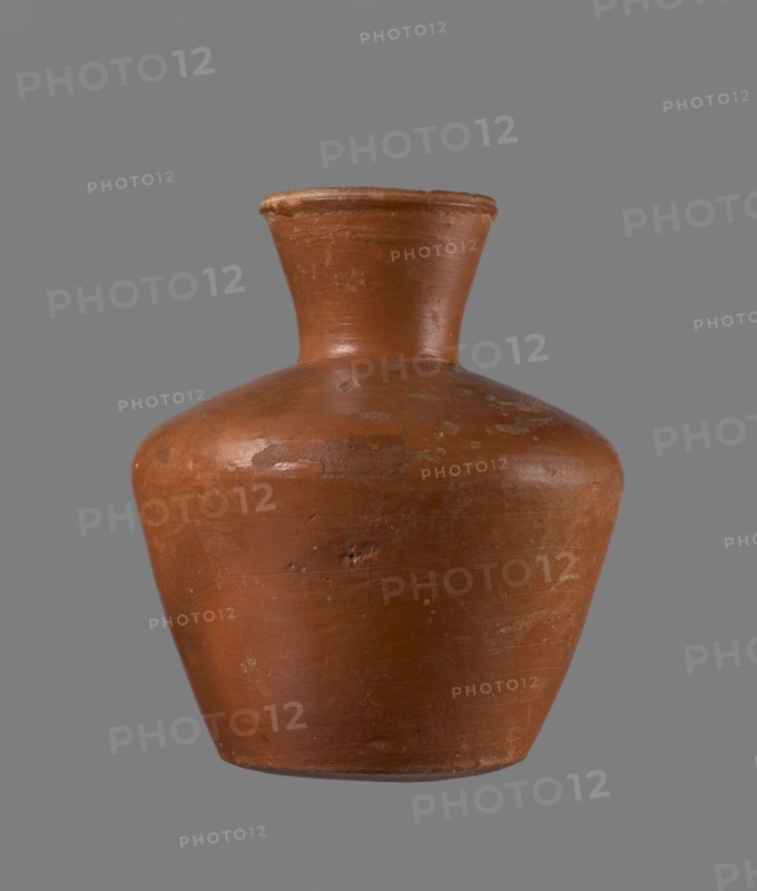 Jug, ceramics, Egyptian pottery, vessel, clay. Medium-sized jug with a biconical body, widest at about half its height. Wide shoulders, not very sloping. Wide, almost cylindrical neck widening towards the spout; neck height about one-third of the vessel. Profiled, irregular spout, slightly raised and extended on one side, forming a small spout. Spout almost triangular in cross-section, with an approximately millimeter-sized cylindrical bulge at the center of the outer profile. Bottom almost flat, very slightly rounded. Made of Nile clay NB1 Vienna System. Neck was formed separately and connected to the shoulders. Outer surface leveled, covered with an engobe, and polished. Inner surface leveled except for the neck, which was also covered with engobe and polished. Color reddish-brown. Well preserved; rim slightly chipped in two places and engobe worn off in places on the outer surface. Analogous to a similar jug from Edfu; dated to the 6th Dynasty. Comparable typology: Reisner, Mycerinu...