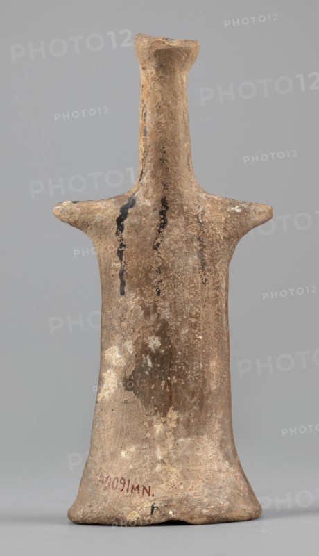 Idol, Female figurine, modeled flat, widens towards the bottom creating an oval base, concave underneath. Shoulders marked with horizontal projections like keels, merge into a narrow, long, cylindrical neck forming one part with the head. Head covered with a polos; a small curled volute touches the polos and beneath it a projection shaped like a bird's beak stylizes the face. Volute and projection are glued on. Linear decoration in black paint. Strands of hair marked with a wavy line: three falling down the back, two over the shoulders. Traces of transverse lines on the volute. Three lines on each shoulder. Bust features a linear ornament of two wavy lines, two straight lines, and three dotted lines alternating. From the waist, three longitudinal wavy lines run down both sides; between them are two faint straight longitudinal lines curving toward the side. At the widening base a transverse line from which lines radiate, emphasizing the oval shape. Back undecorated. Faint traces of brow...