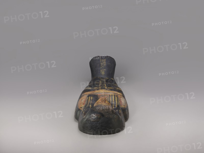 Lid of an anthropoid sarcophagus of a woman with clearly modeled legs. The head is sculpturally modeled—very carefully. The face is triangular with a strong, flat, strongly forward chin. Large, almond-shaped eyes are plastically developed. The nose is straight, the mouth is small with fleshy lips, clearly highlighted. The wig is schematically designed. On the chest is a richly polychromed nine-row necklace. Below is a representation of a pectoral cross in the form of a winged vulture. The offering formula running through the center and on the sides divides the surface of the lid into six undecorated fields. Sacrificial formulas, vulture iconography, necklace iconography, black type, wigs, hieroglyphs. c. 1400–c. 1295 BC; New Kingdom, late 18th Dynasty. Deir el-Medina grave 1352, western necropolis. Sarcophagus lid; height 193 cm, width 53 cm., A painted sculptural object resembling a reclining human figure with a stylized face and crossed hands, shown from a head-on perspective. The su...