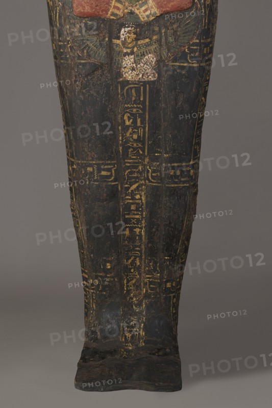 Lid of the sarcophagus of a man named Setau, Setau ca. 1479–1295 BC. Sarcophagus lid, c. 1479–c. 1295 BC; New Kingdom, late 18th Dynasty, from Deir el-Medina tomb 1352, western necropolis. Height 192 cm, width 50 cm, depth 34 cm. A vertical band of inscription runs through the center – the sacrificial formula. Two columns of text along the edge of the lid and three columns across divide the surface into six fields. The legs are clearly defined, the arms are modeled, the hands are clenched. On the chest is a richly polychrome seven-row necklace; below the hand is a depiction of the winged goddess Nut. The head is sculpturally detailed: face painted red with large almond-shaped eyes set slightly obliquely; eyeballs clearly defined; pupils and eyebrows highlighted in black. The nose is straight and strongly flattened; the mouth small with wide, full lips. The wig is schematically decorated with yellow stripes; the face and hairstyle painted black and rendered in the round. Setau once had ...