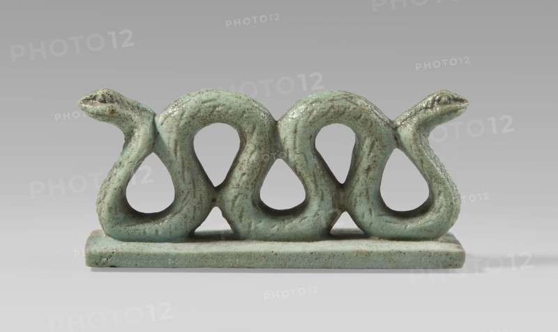 Amulet – two-headed snake, two-headed snake with vertical coils on a base, with delicately carved scales and snouts; snakes, animals; protective amulet; Egyptian art; Late Period, 664–332 BC, Egypt; amulet; height 3.3 cm, width 7 cm, depth 1.5 cm., A glazed sculptural object in a pale green color with darker green and brown speckling sits on a flat rectangular base of the same color; the main form consists of a horizontal sequence of soft, looping shapes that create three large open teardrop-like holes and end in two stylized serpent heads at each side, both heads sharing the same pale green glaze with visible texture and irregularities, all set against a neutral gray background.