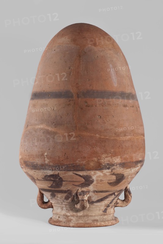 Vessel, Amphora with an ovoid body that tapers towards the bottom; rounded bottom. The vessel is widest at approximately 3/4 of its height. Shoulders are wide and sloping. Neck is wide, profiled, ending in a widening rim, flat on top. Four small cylindrical lugs connect the neck to the shoulders. Decoration painted and impressed: a 2 cm wide painted band halfway up the body and the same band at the junction of body and shoulders. Shoulders feature a painted floral decoration — a plant tendril with tripartite leaves in a purple-brown color; decoration not very carefully executed. Imprinted string lines visible around halfway up and slightly below the shoulders. Clay color light beige. Vessel glued together from several original fragments with missing pieces filled in with plaster. Surface worn in places. Date: 332–30 BC, Ptolemaic Period. Place of origin: Edfu. Function: vessel. Materials: clay; ceramics. Dimensions: height 57.5 cm; rim diameter 20.4 cm; body diameter 36 cm., A large ro...