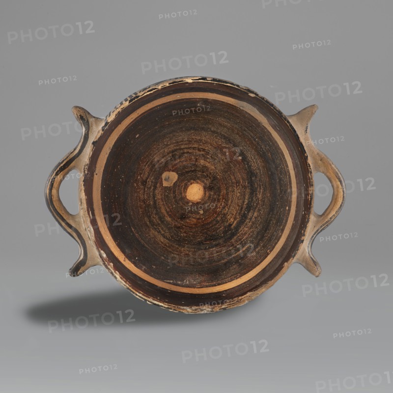 Skyphos mug with depictions of ducks, Late Geometric period, ca. 725–700 BC. Skyphos with a profiled belly. Just below the rim are two painted bands with a delicate line. The metopes depict ducks with long necks and legs, in front of which are stylized flowers; one bird image is very poorly preserved. Behind each bird's head is a swastika motif. Silhouette technique? Vices placed at the maximum width of the belly. Inner surface covered with matte, faded paint. A reserved line is left a short distance from the bottom; the bottom is undecorated. Technology: visible traces of turning. Varnish worn away in places. Clay light yellow with many inclusions. Surface shows significant abrasions and chips. Condition: spout damaged. Visible conservation additions old glue. Clay color: black 7.5 YT 2.5/1; red 10 R 4/4. Provenance/attribution notes: attributed to Attica; dated to Late Geometric 9th–8th century BC. Dimensions: height 9.0 cm; width 19.6 cm; depth 15 cm; weight 0.352 kg., A round shall...