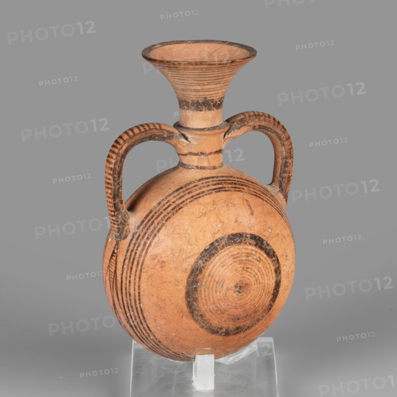 Bottle amphoriskos, Amphora with a round, slightly flattened flask-like belly. Brown-black decoration of concentric circles of varying thickness on the belly, horizontal lines on the rim, and a fine zigzag. Geometric motifs; Cypriot pottery. 1050–750 BC Cypriot–Geometric Period, Cyprus. Vessel. Height 10.4 cm; width 6.7 cm., A ceramic vessel with a rounded, flattened body and a flared neck, supported on a clear stand, shown against a gray background; the vessel is primarily terracotta orange with darker brown painted concentric circular bands on the body and neck, and darker brown striped decoration along the curved double handles; the surface shows some wear and small lighter speckles.