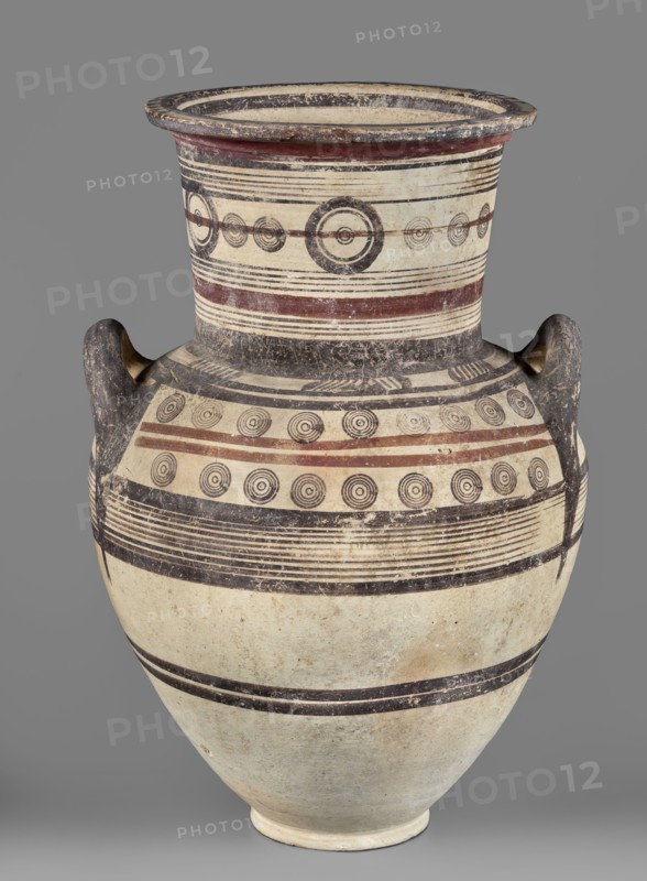 Amphora, unknown Cypriot workshop, Cypriot pottery, Amphora with a low foot, wide neck, and upturned vices. Rounded belly. Surface covered with geometric decoration emphasizing the structure of the vessel. Decoration composed of concentric bands and circles. 850–700 BC Cypriot–Archaic Period I. Cyprus, vessel, height 54 cm, width 35 cm, weight 7.40 kg., A large ceramic vessel with a rounded body, a wide flaring neck, and two loop handles, decorated with concentric circle motifs and horizontal banding in black and reddish-brown on an off-white or cream ground; the neck and shoulder show several parallel thin black lines and a few broader reddish-brown bands, with rows of circular target-like motifs in black; the handles are dark and worn, showing textured surface with darker gray or black coloration; the lower body has broad horizontal black bands and a slightly mottled off-white surface with areas of light tan discoloration; the rim interior appears darker with black and cream rings, a...