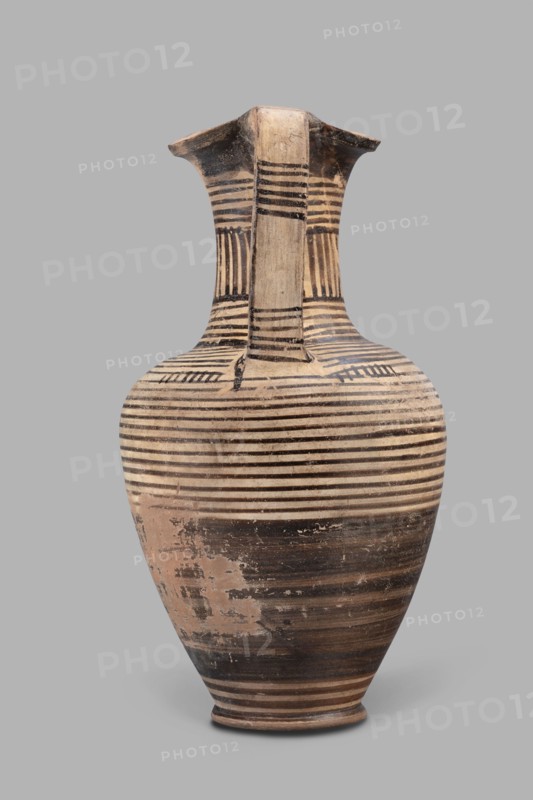 Oinochoe, Geometric oinochoe with a low foot, a gradually widening belly, distinct shoulders, a slender neck, and a tripartite rim characteristic of this vessel form. The vise runs from the shoulder to the rim. Halfway up the belly it is covered with black finish; the rest of the vessel is decorated with closely arranged parallel horizontal lines encircling the entire vessel. The central part of the neck is decorated with vertical stripes. Oinochoe was used for drawing and pouring wine Greek: oinos - wine and is a typical Greek vessel. End of the 8th century BC dated by Papuci Vladyka to the end of the 8th–beginning of the 7th century BC; described as an Italian imitation of the Proto-Corinthian workshop, Cumae workshop. Southern Italy Italy. Vessel, oinochoe. Weight 0.476 kg; height 23.2 cm; diameter 12.2 cm., A tall ceramic vessel with a narrow base that widens into a rounded body and then tapers to a flared neck and rim, decorated with a pattern of horizontal stripes and bands. The ...